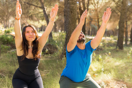 Young adults practicing yoga together in a forest on a sunny mid-flat morning