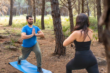 Young people practicing yoga in a forest with their blue mat on a sunny day for relaxation.