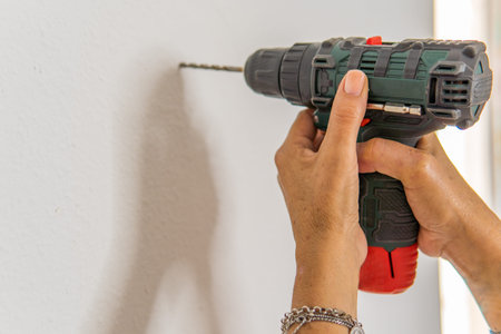 unrecognizable person using a drill to make a hole in his house.