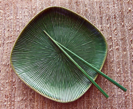 Square green plate and green chopsticks on sisal mat.の写真素材