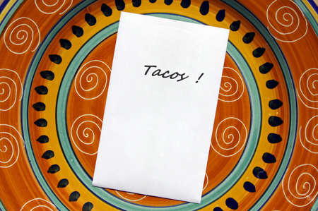 The word TACOS! printed on white paper with copy space on top of colorful Mexican style plate.の写真素材