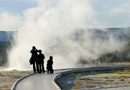 Silhouetted Tourists Photographing a Volcanic Geyserの写真素材