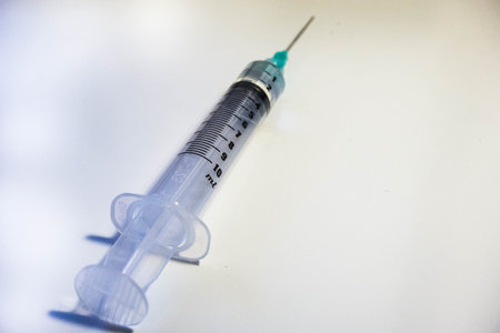 A green tipped syinge containing 2ml of water at a low angle