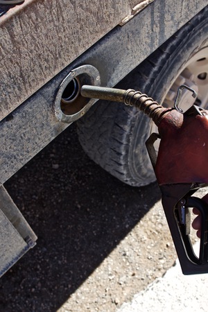 Hand Holding Diesel Fuel Pump Close to Truck Fuel Tankの写真素材