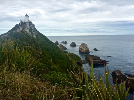 Lighthouse overlooks Rocky Rugged Shoreline on the Beaches of Southern New Zealandの写真素材