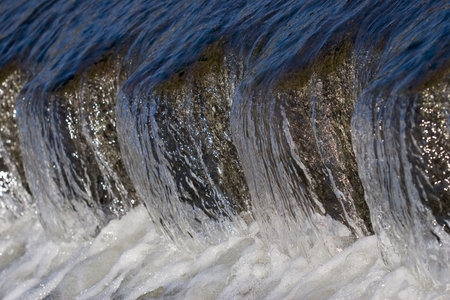 Clear blue sparkling water cascading over a small weir