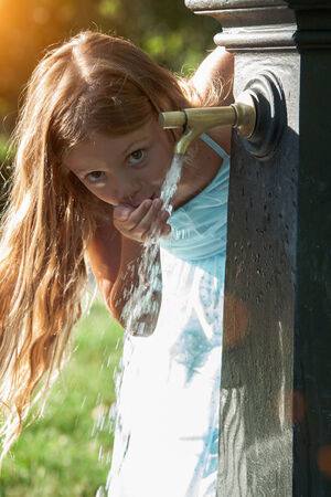 Little quenches thirst at the fountainの写真素材