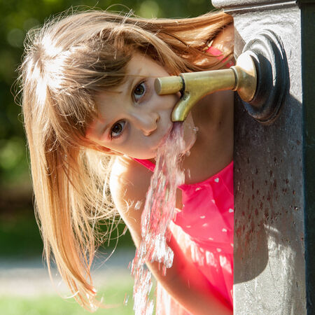 Little quenches thirst at the fountainの写真素材