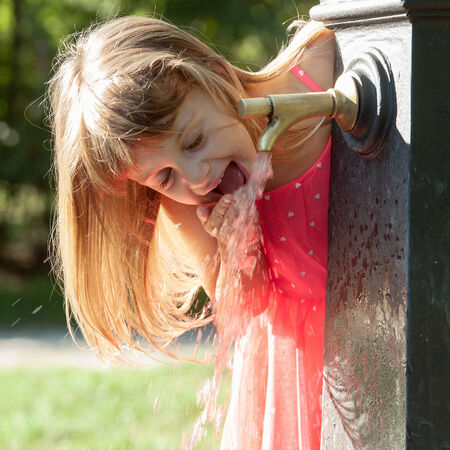 Little quenches thirst at the fountainの写真素材