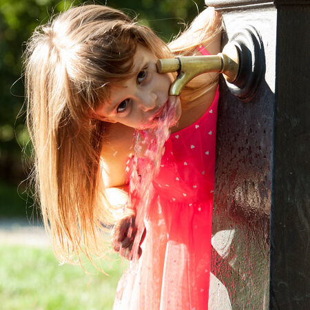 Little quenches thirst at the fountainの写真素材