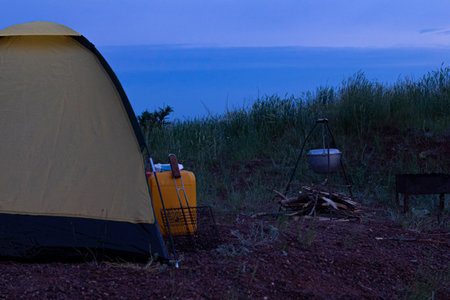 Tent bonfire orange canister on the background of the sunset sky on a camping trip in the evening