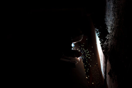 male worker welds steel pipe of household heating at night