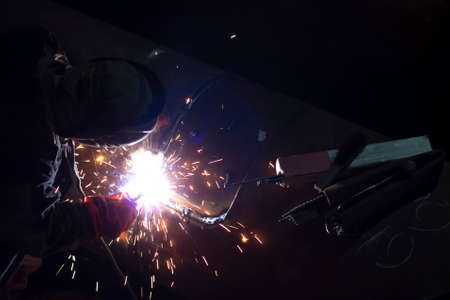 male worker welds steel pipe of household heating at nightの写真素材