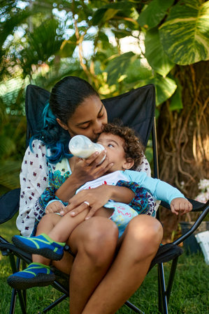 Portrait of mother feeding her son with milk in the garden.の写真素材