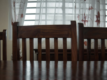 Chairs at a dining table casting shadows on the tableの写真素材