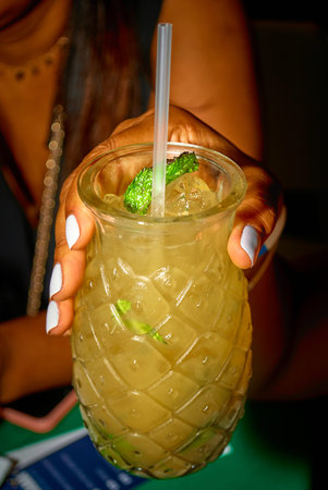 cocktail in a glass in the hands of a girl on a green background