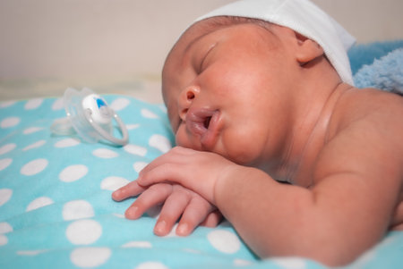 Newborn baby boy sleeping on a blue blanket with a pacifierの写真素材