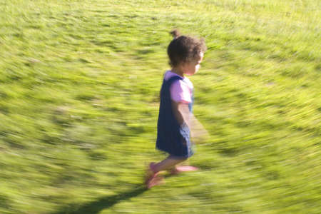 A young mixed race girl runs through a grassy fieldの写真素材