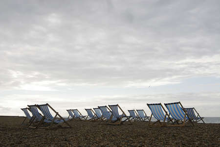 A group of empty deckchairs on a cloud covered beach in the early morningの写真素材