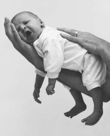 A yawning baby resting on his father's hand.の写真素材