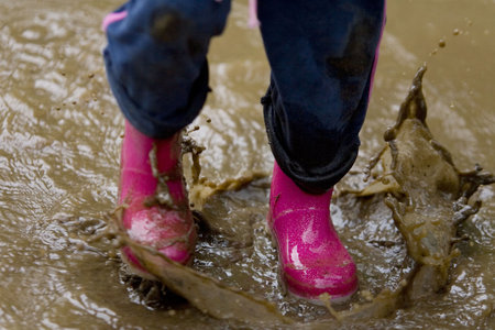 A little girls pink boots splashing in a muddy puddleの写真素材