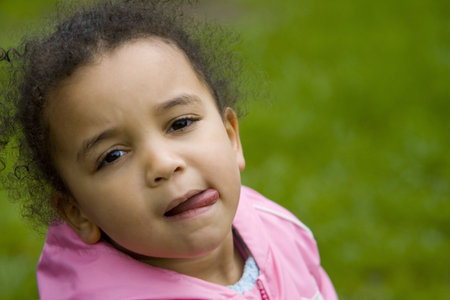 A little mixed race girl in pink tongue out and thinking