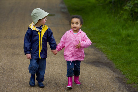 A little boy and girl wearing wellington boots holding hands and walking through a country parkの写真素材