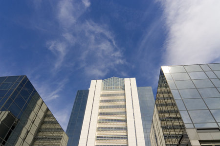 Glass fronted skyscrapers reach up into a bright blue sky with a few wispy clouds