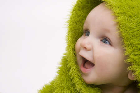 A beautiful smiling baby wrapped in a furry green blanketの写真素材