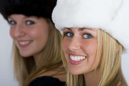 Two beautiful Russian women wearing fur hats, shot in three quarter profile, one in focus one out but both smiling for the cameraの写真素材