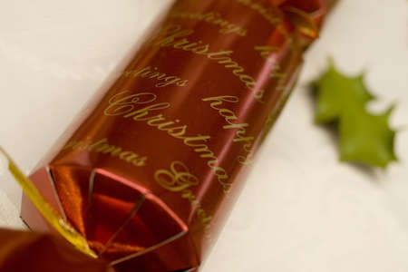 Close up macro shot of a Christmas cracker with a holly leaf in the background.の写真素材