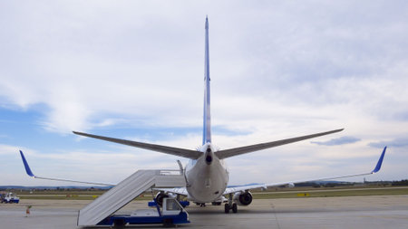 Panoramic shot of an airliner parked on the runway with the steps in place for passengersの写真素材