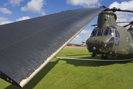 A Boeing CH-47 Chinook with the rotor blades all tied down and one of them in close up in the...