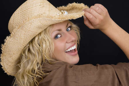 Studio shot of a beautiful young woman with bright blue eyes wearing a straw cowboy hat and laughingの写真素材