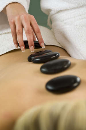 Hot basalt stones being applied to a young woman's backの写真素材