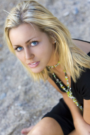 Portrait of a beautiful young blond woman sitting on a beach の写真素材