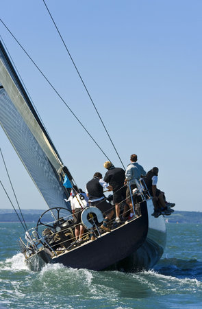 A fully crewed racing yacht catching the wind