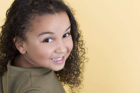Studio shot of a beautiful young mixed race girl smiling and looking back over her shoulderの写真素材