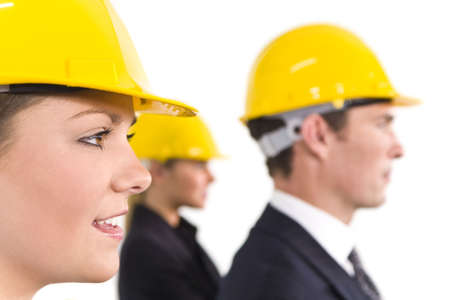 A selective focus industrial concept shot showing 2 women and a man dressed in hard hats. The focus is on the woman in the foregroundの写真素材