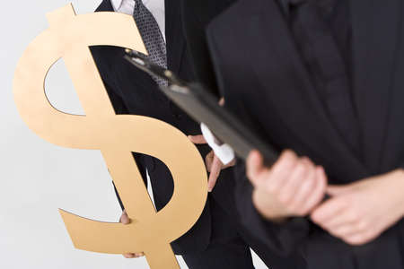 Concept shot showing business people standing in a line, the last of whom is carrying a large golden dollar symbolの写真素材