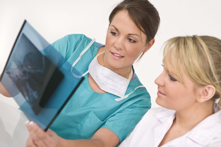 A female doctor and her nursing colleague examining an X-ray of a human skull