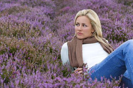 A beautiful blond haired blue eyed model laying down among purple heatherの写真素材