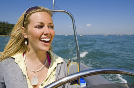 A stunningly beautiful young woman driving a powerboat and having fun in a beautiful sun drenched...
