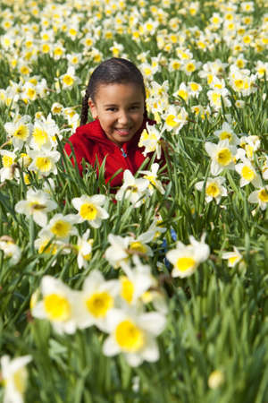A beautiful young mixed race girl playing in a field of daffodilsの写真素材