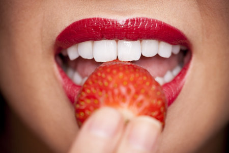 Macro close up of a beautiful female mouth eating a fresh strawberryの写真素材