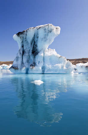 A glacial iceberg and its symmetrical reflection floating on the Iceberg Lagoon, Jokulsarlon, Icelandの写真素材