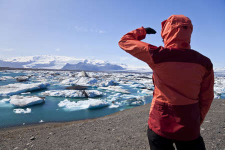 Female hiker looking across the Iceberg Lagoon, Jokulsarlon, Iceland filled with glacial Icebergs with the Vatnajokull Glacier in the background, Europe's biggest glacier. The focus is on the Icebergs. Shot in summer 2009 when the lagoon had the greatest の写真素材
