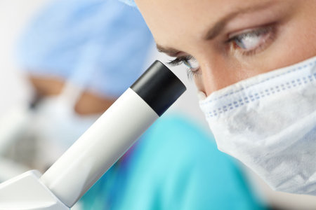 A female medical doctor or scientific researcher using her microscope in a laboratory, with her...