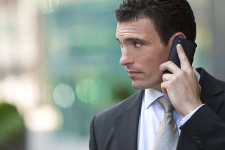 A young male executive on his mobile phone in a modern cityの写真素材