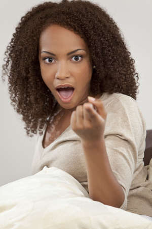 A beautiful miced race African American girl looking shocked, surprised and pointing at the cameraの写真素材